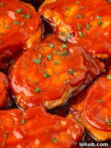Boneless pork chops coated in BBQ sauce in a large skillet.