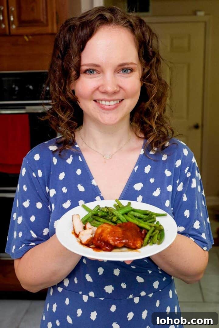 Crispy Oven-Baked BBQ Boneless Chicken Thighs 10 Kelsey Smith holding a plate with BBQ chicken thighs and green beans.