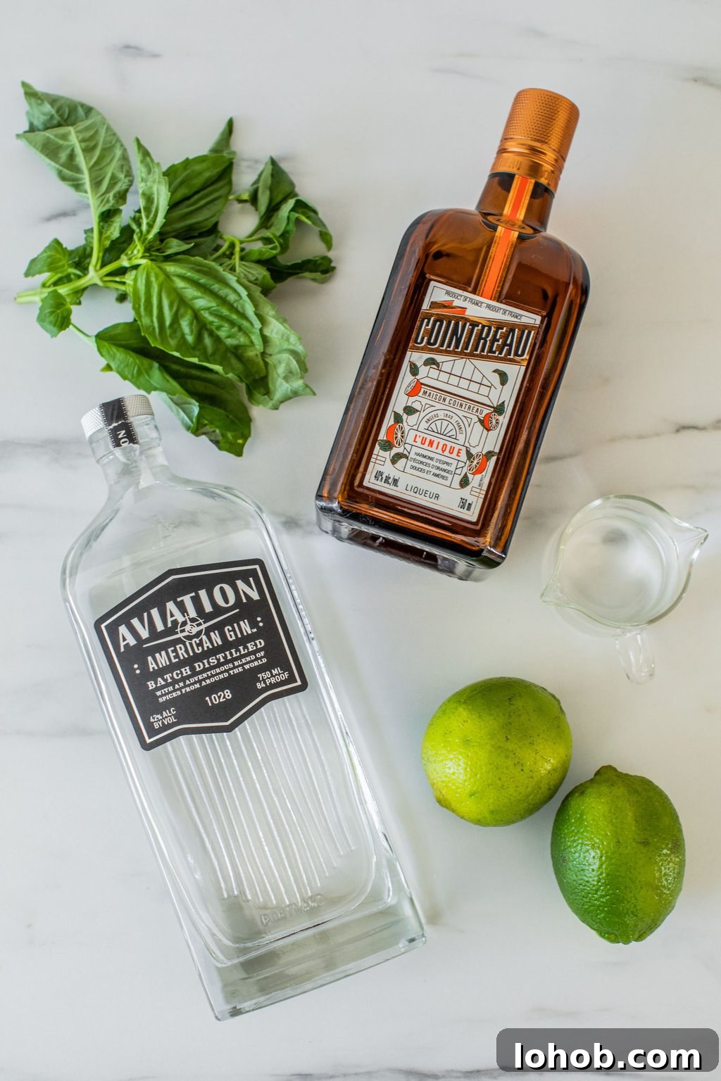 gin, basil leaves, Cointreau, lime, and simple syrup on a white marble countertop