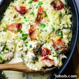 Spinach, Chicken & Artichoke Casserole Recipe with Light Cream Sauce 12 spinach artichoke and chicken in a black baking dish with a wooden spoon.