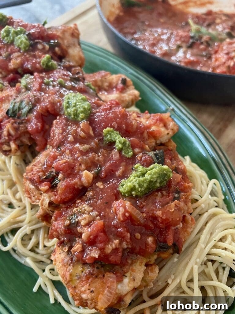One-Pan Chicken Pomodoro Recipe for Quick Weeknight Dinners 18 One Pan Chicken Pomodoro over a bed of spaghetti with garlic and olive oil, topped with a few spoonfuls of basil pesto.