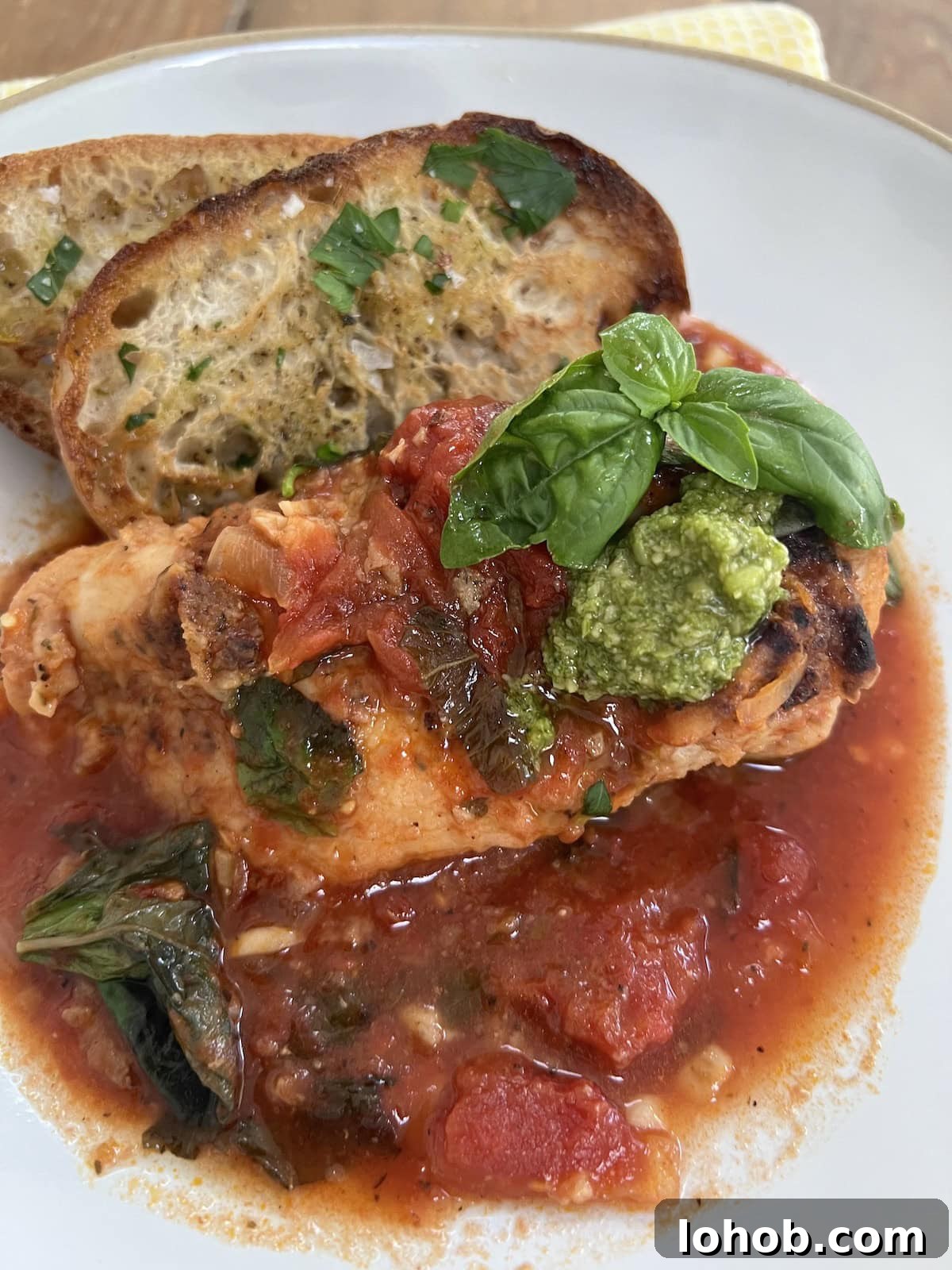 One-Pan Chicken Pomodoro Recipe for Quick Weeknight Dinners 19 Easy Pomodoro Chicken on a white dinner plate with toasted bread and basil garnish.