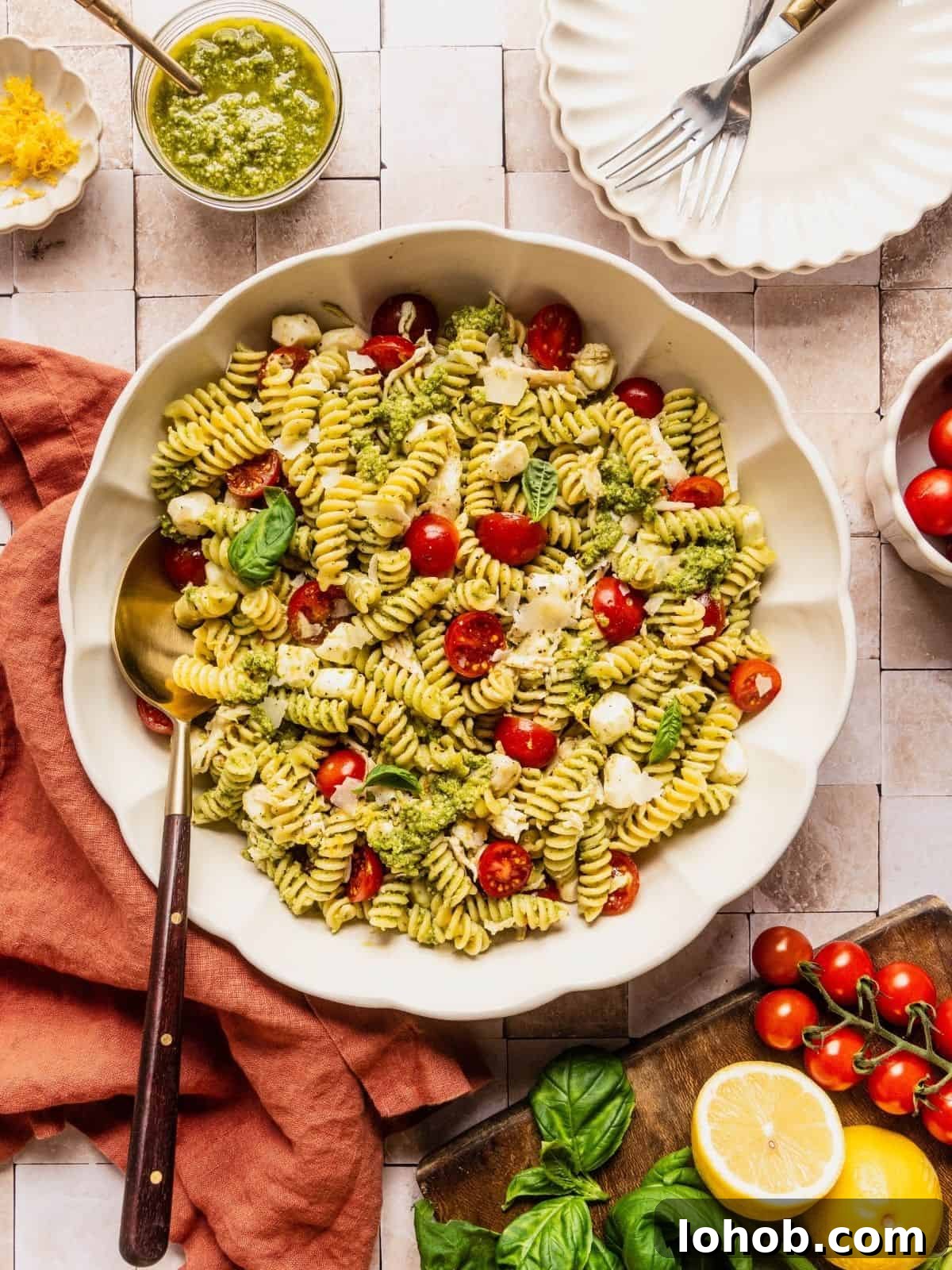 Grilled Chicken Pesto Pasta Salad with Sun-Dried Tomatoes 15 Chicken and pesto pasta salad in a large serving bowl garnished with basil leaves and shaved parmesan.