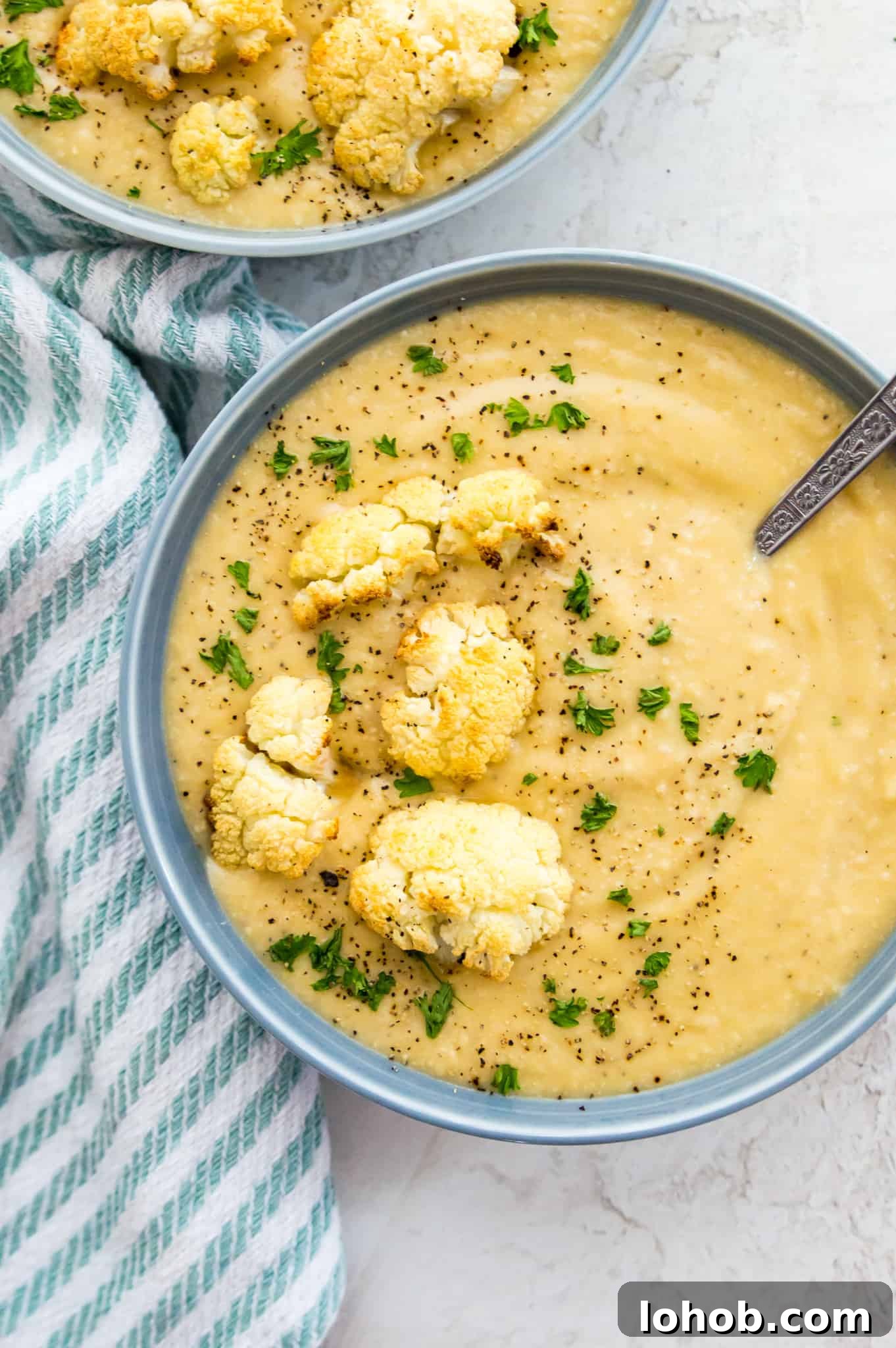 Instant Pot Cauliflower Soup Bowls of cauliflower soup garnished with fresh parsley, roasted cauliflower and black pepper.