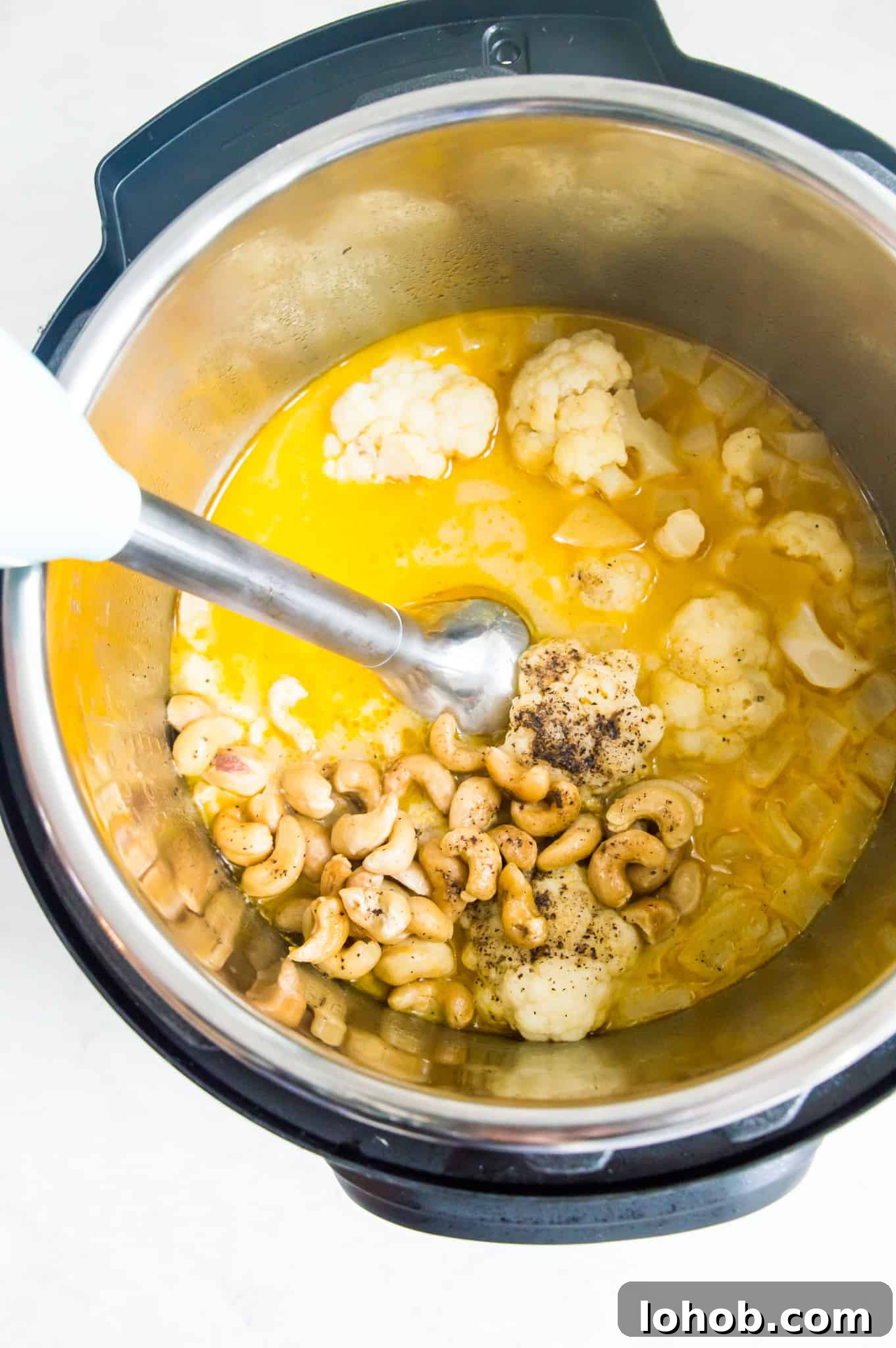 Instant Pot Creamy Cauliflower Soup — Vegan & Low-Calorie 5 An Instant Pot with cashews, broth and cauliflower in it with an immersion blender in the pot.