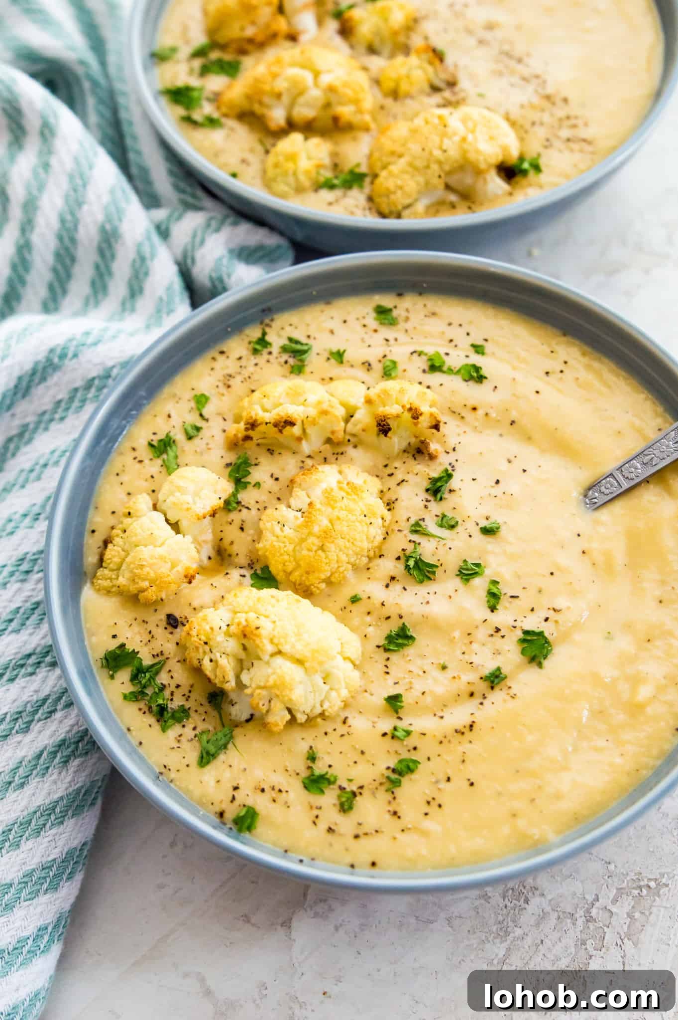 Cauliflower Soup Bowls of creamy cauliflower soup topped with roasted cauliflower, black pepper and fresh parsley.
