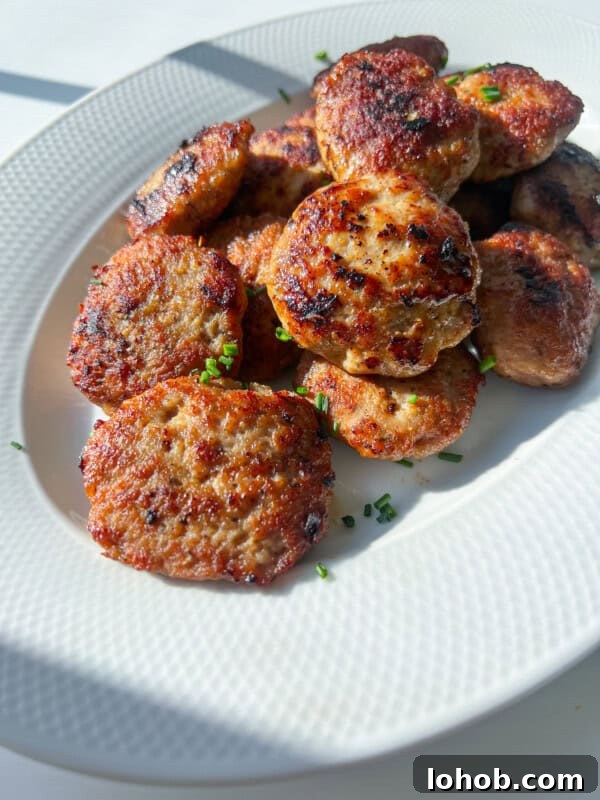 Homemade Breakfast Sausage Recipe for Juicy Flavor and Quick Prep 4 A white plate filled with several golden-brown, pan-fried meatballs, garnished with chopped chives.