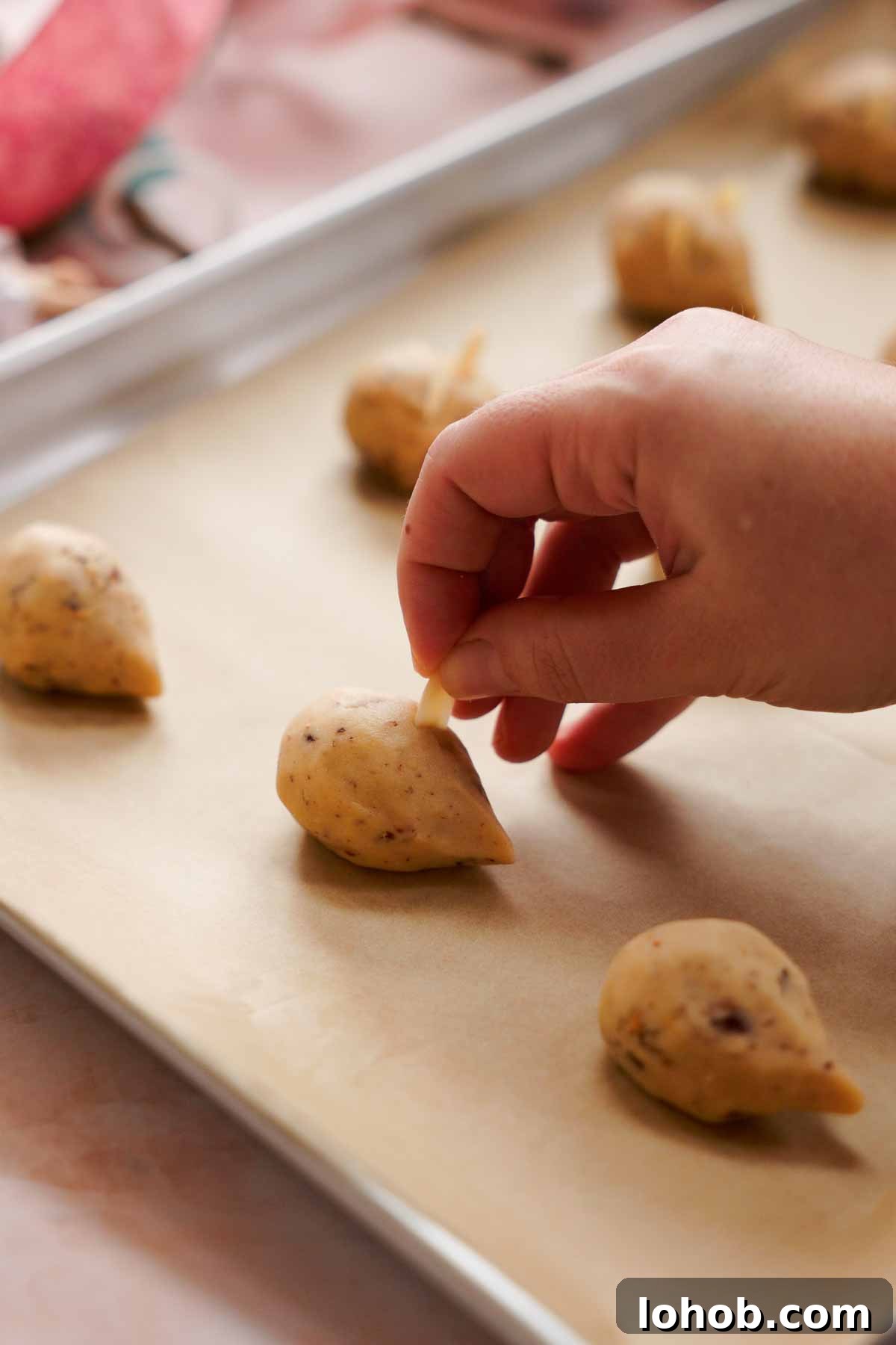 adding sliced almonds as ears onto christmas mice cookies