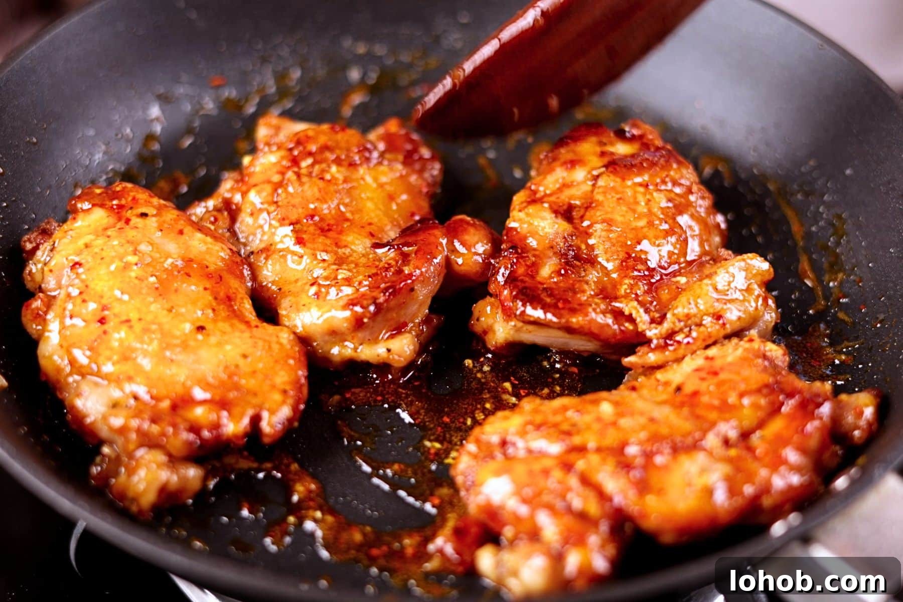 Crispy Honey Garlic Chicken Thighs — One-Pan Recipe 6 Tossing the crispy chicken thighs with the honey garlic sauce in the pan.