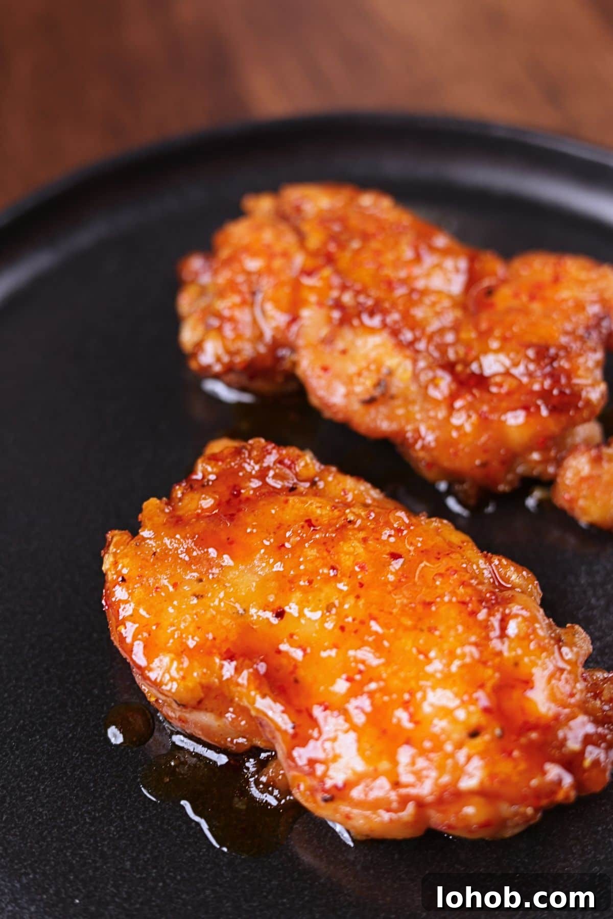 Crispy Honey Garlic Chicken Thighs — One-Pan Recipe 7 Crispy honey garlic chicken thighs served on a black platter with a glossy sticky glaze.
