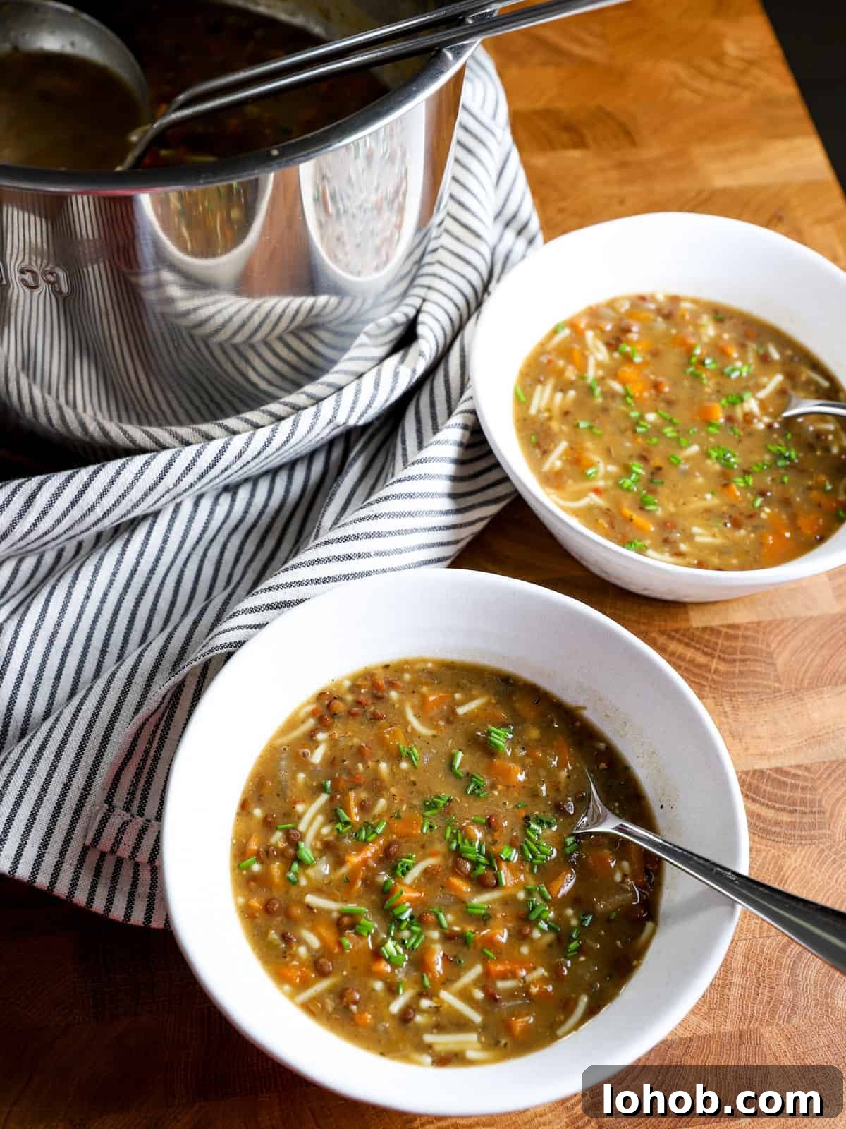 Hearty Vegan Lentil and Vegetable Noodle Soup Recipe 3 Photo showing instant pot in the background and two bowls of soup served in front.