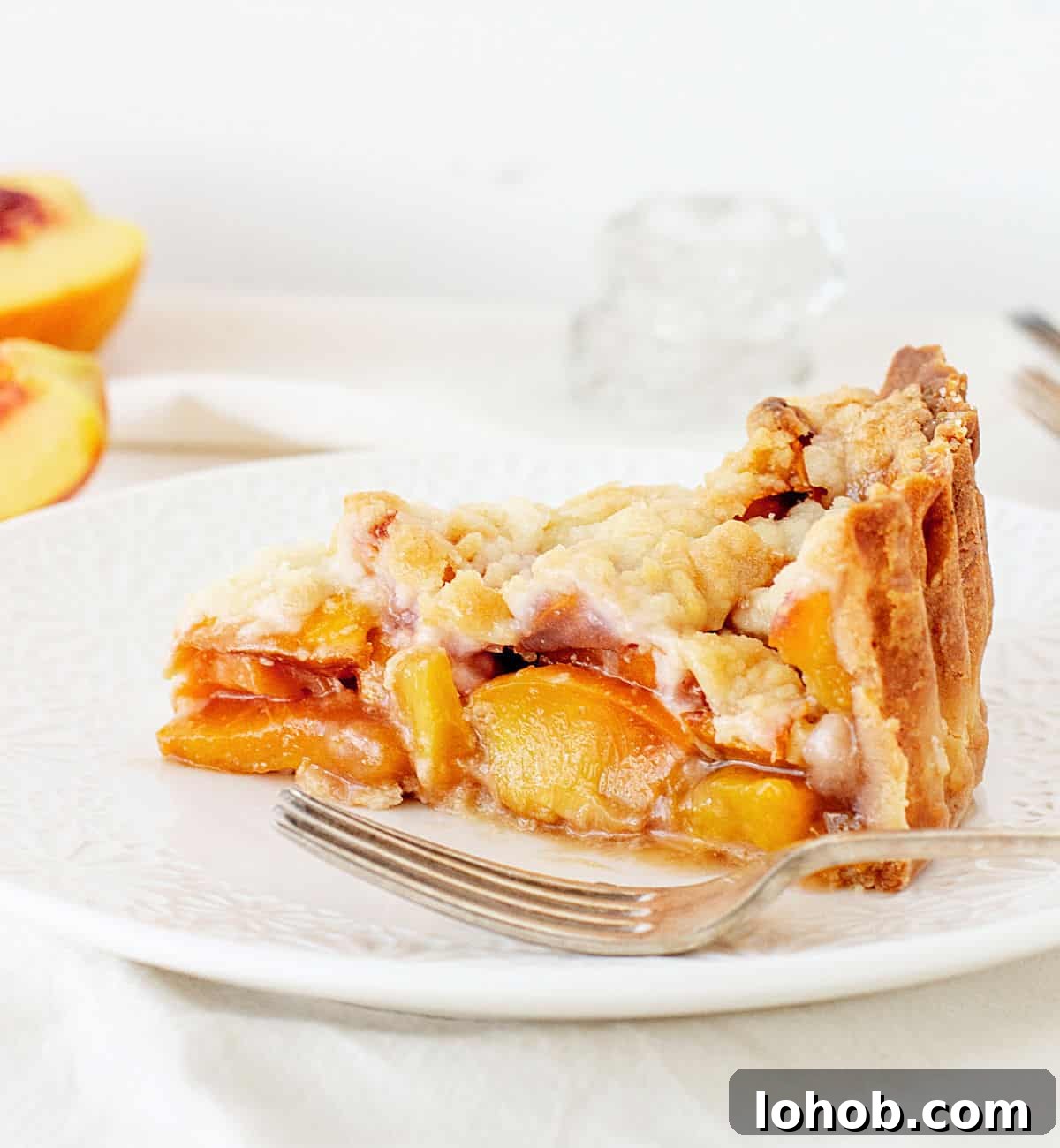 Perfect Peach Pie with Buttery Crumb Topping 2 Slice of peach crumb pie on white plate, white background.