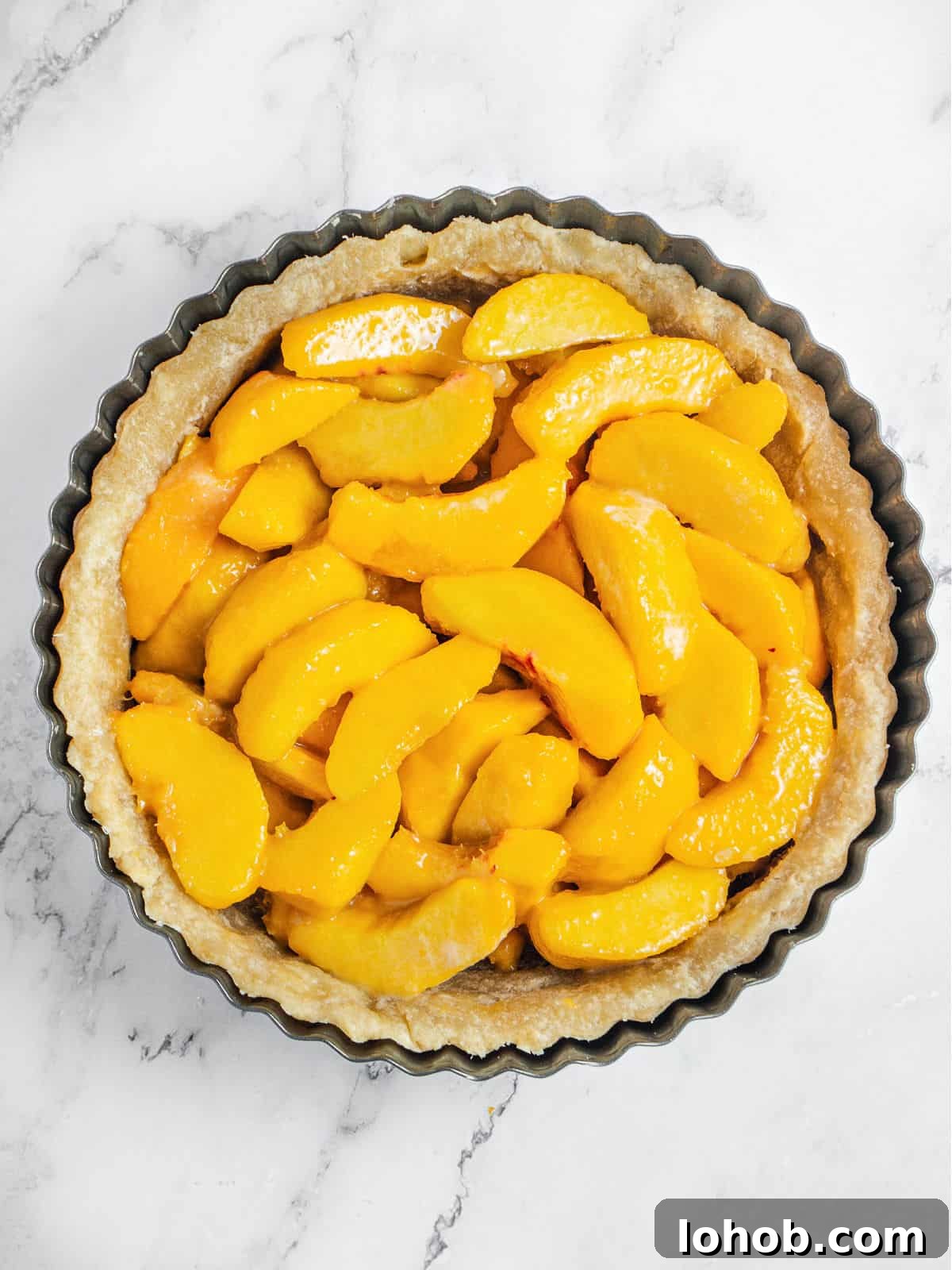 Perfect Peach Pie with Buttery Crumb Topping 6 Dark metal pie pan with unbaked peach pie filling. White marble background.