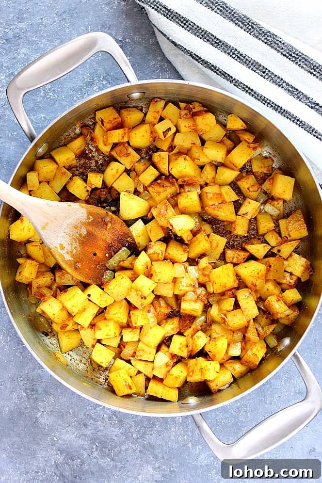 potatoes sauteing in curry spices in pan