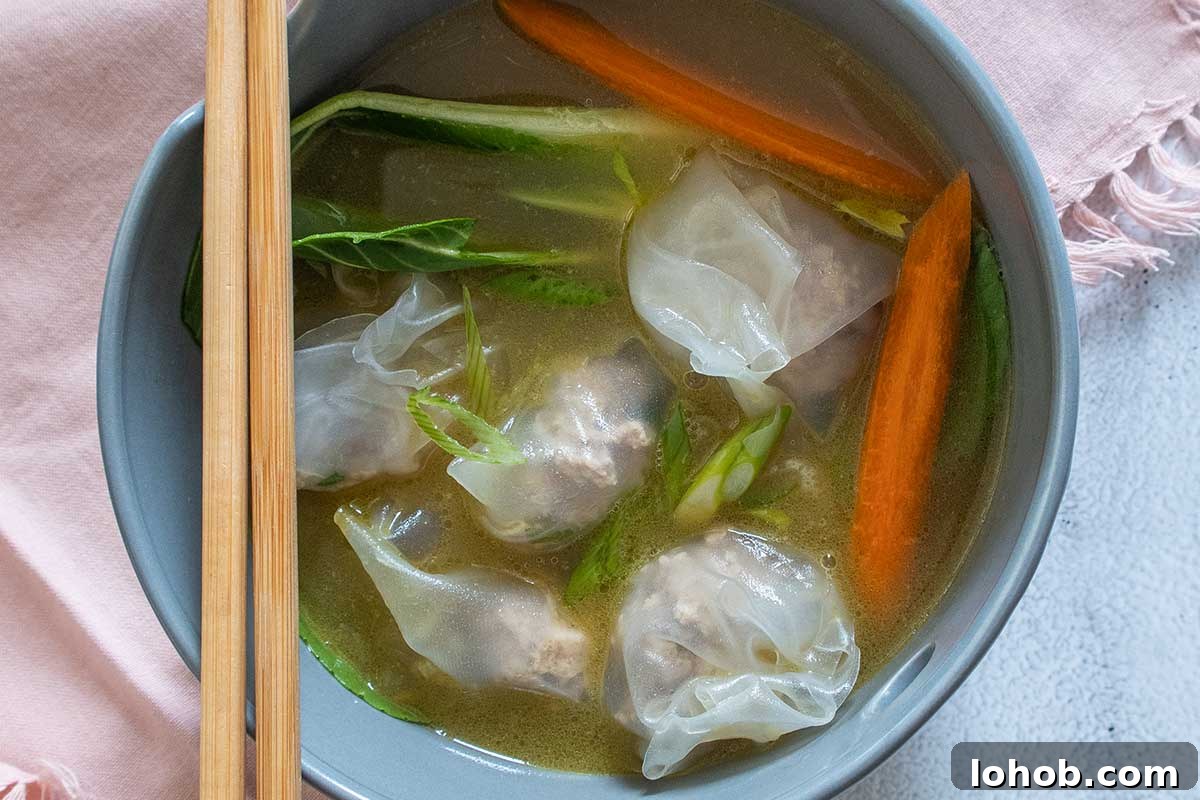 wonton soup with dumplings, bok choy and carrots in a bowl