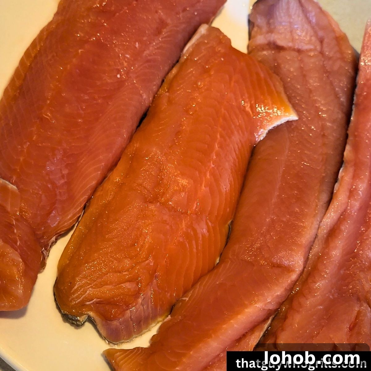 Grilled Salmon in Foil Packets with Lemon and Herbs 3 Salmon fillets raw on a plate