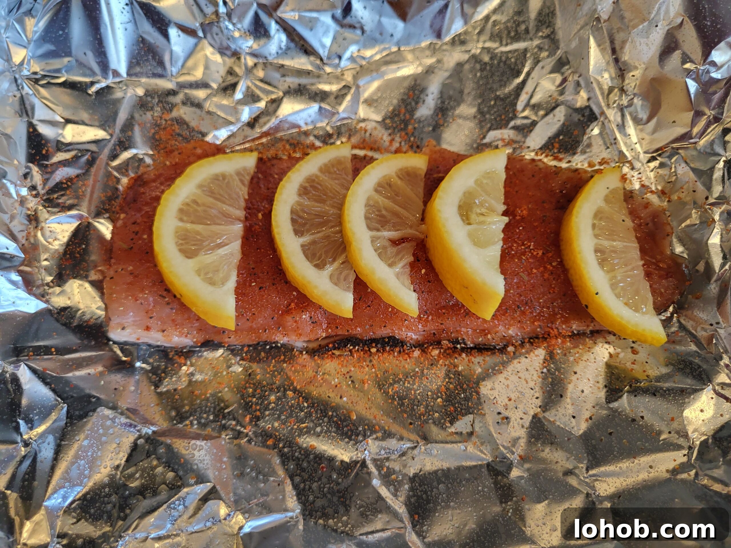 Grilled Salmon in Foil Packets with Lemon and Herbs 5 Salmon fillet on foil seasoned with lemon wedges