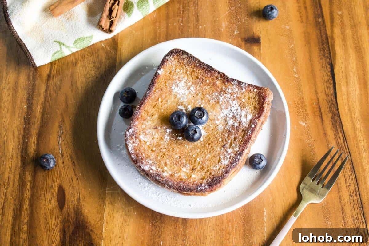 Air fryer french toast slices with syrup and blueberries on plate.