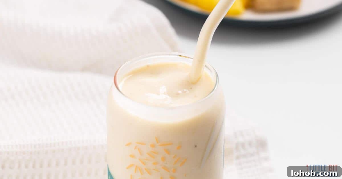 Pineapple banana smoothie in glass with straw.