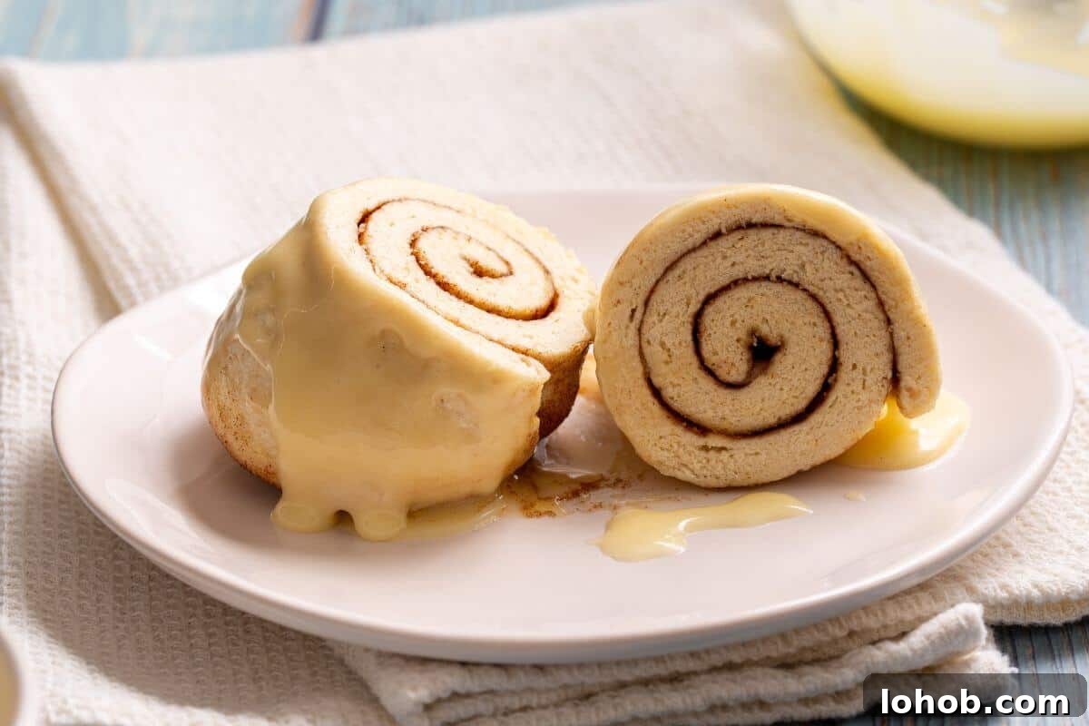 Cinnamon roll made in a mug sliced in half on plate.