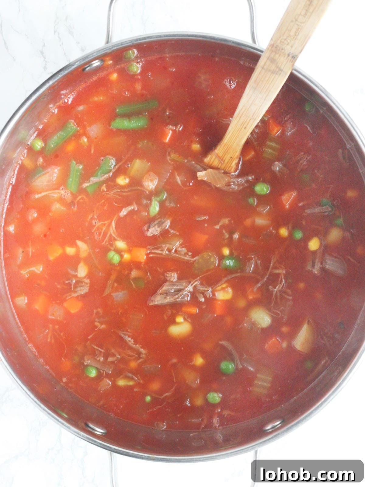 Hearty Vegetable and Beef Soup Recipe for Family Meals 4 pot of vegetable beef soup with a wooden mixing spoon