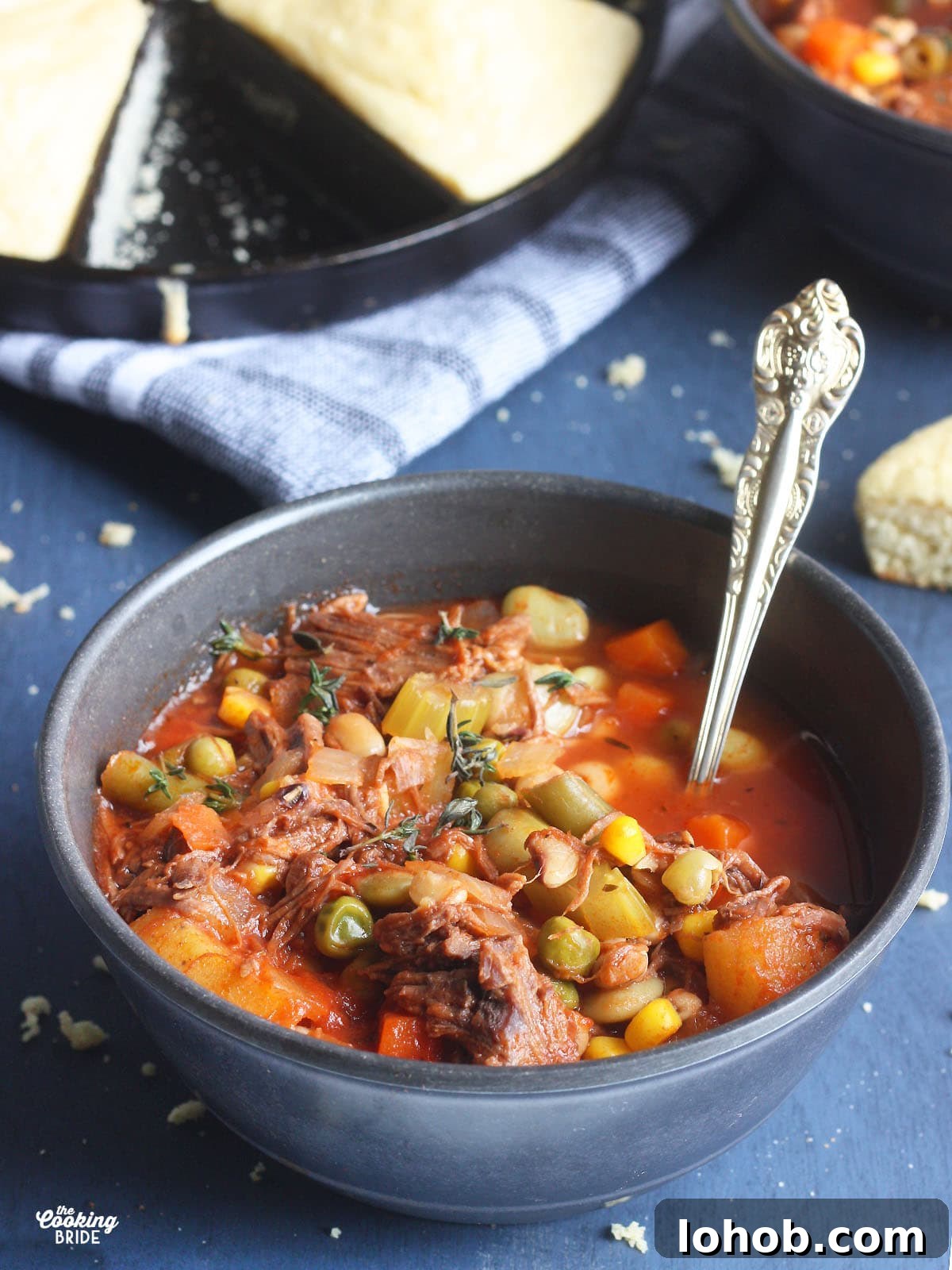 Hearty Vegetable and Beef Soup Recipe for Family Meals 6 bowl of vegetable beef soup with a spoon and a pan of cornbread in the background