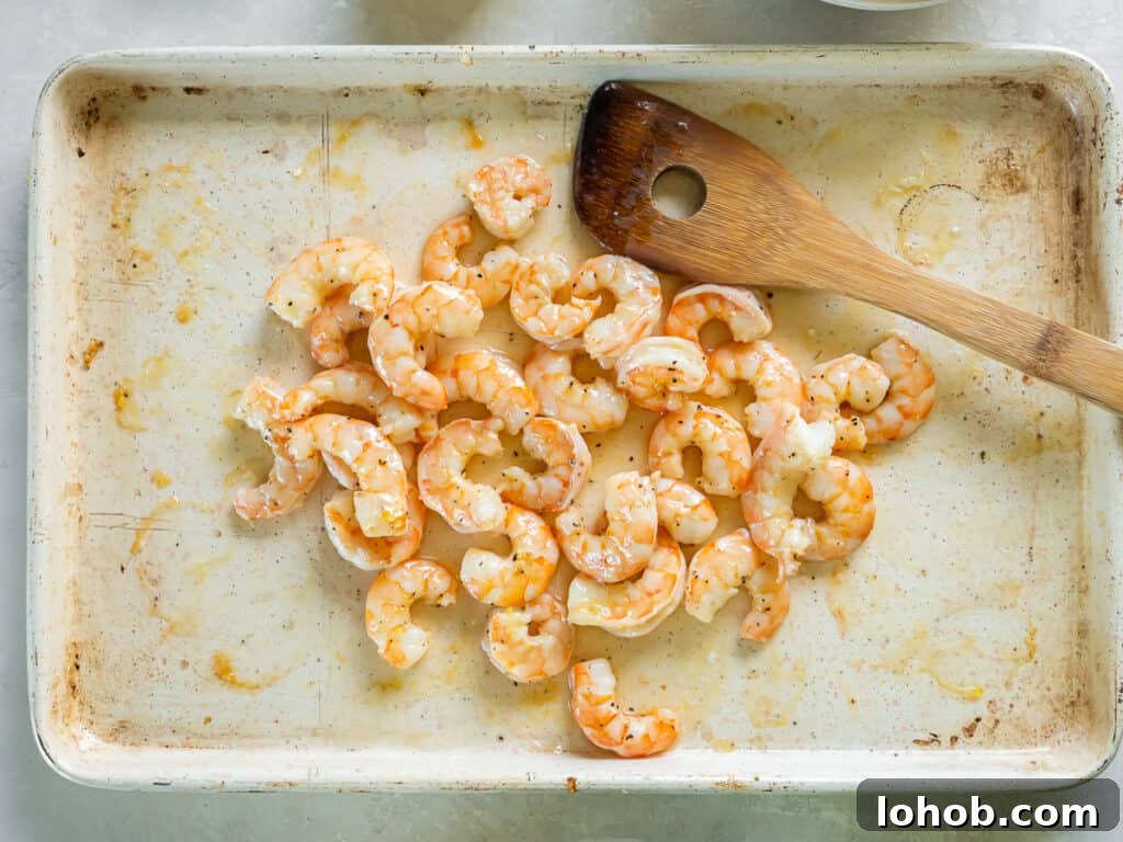 Grilled Shrimp Caesar Salad with Crispy Parmesan Croutons 11 Roasted shrimp on a baking sheet with a wooden spatula.