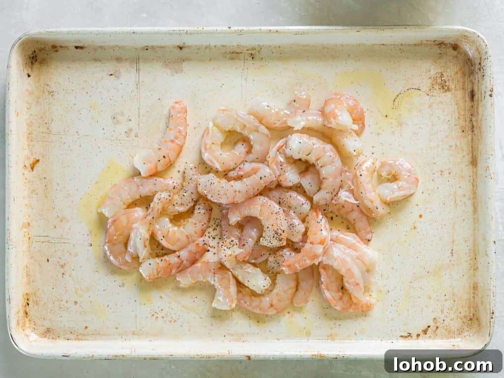 Grilled Shrimp Caesar Salad with Crispy Parmesan Croutons 9 Shrimp drizzled with oil on a baking sheet with a wooden spatula.