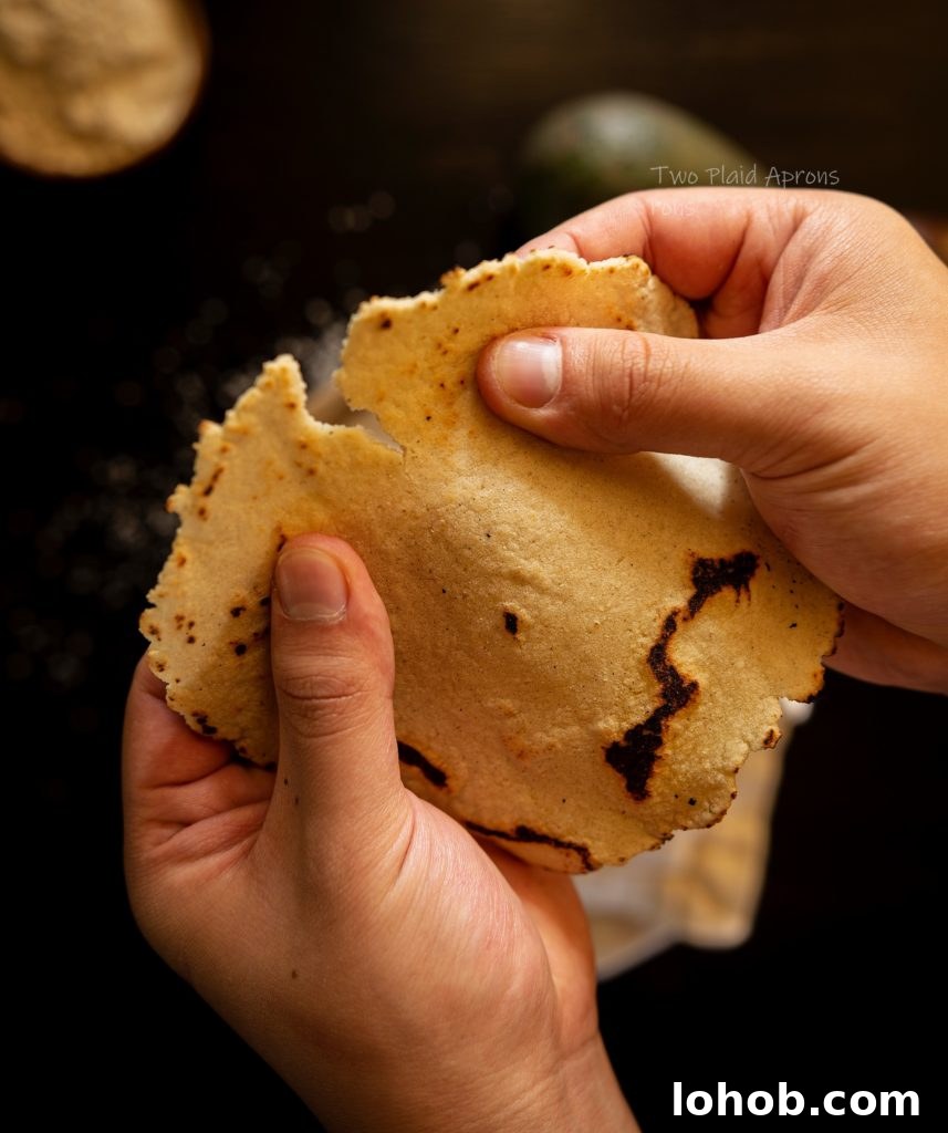 Homemade Corn Tortillas with 3 Simple Ingredients 8 Tearing a corn tortilla in half.