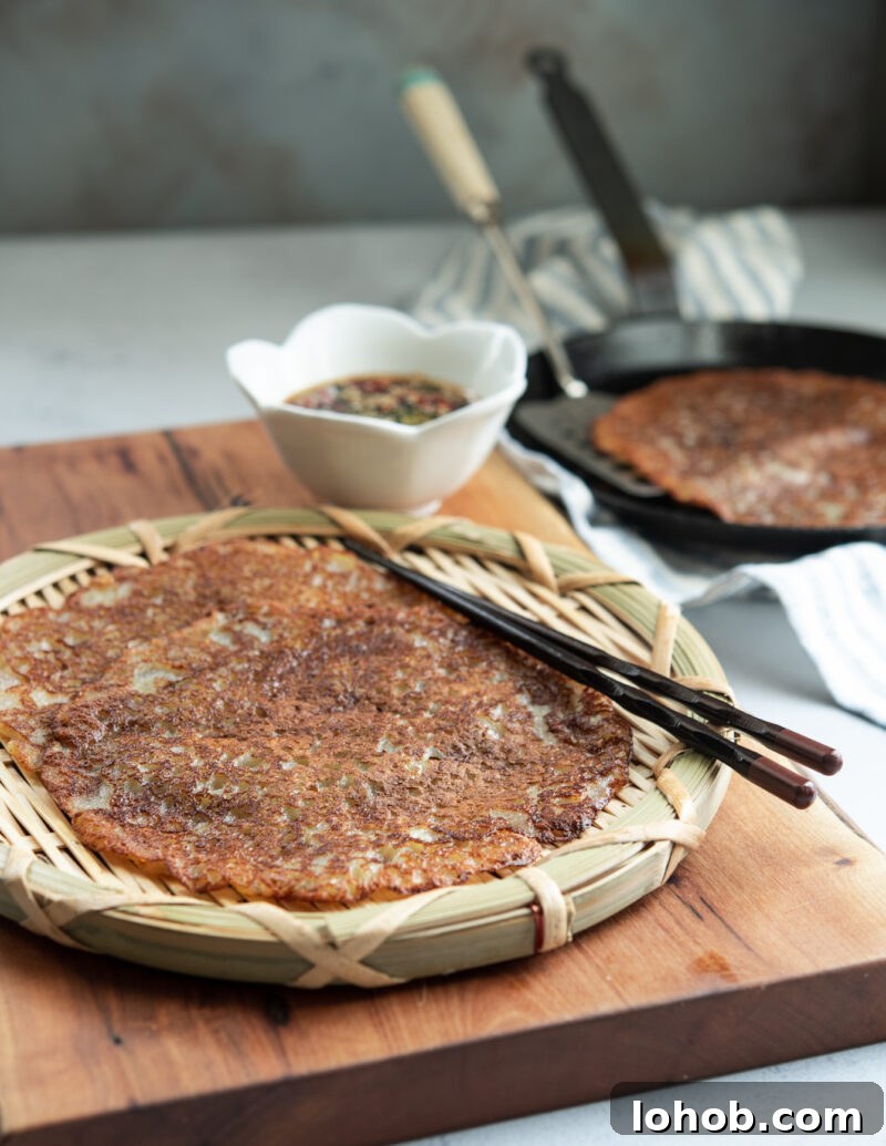 Golden crispy Korean potato pancakes served on a woven plate with chopsticks and soy chili dipping sauce