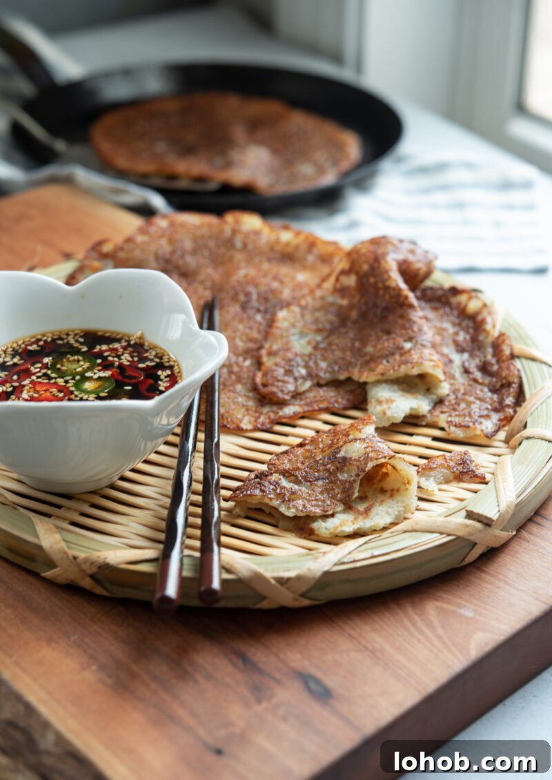 Thin Korean potato pancakes (gamja-jeon) served on a woven plate with soy chili dipping sauce
