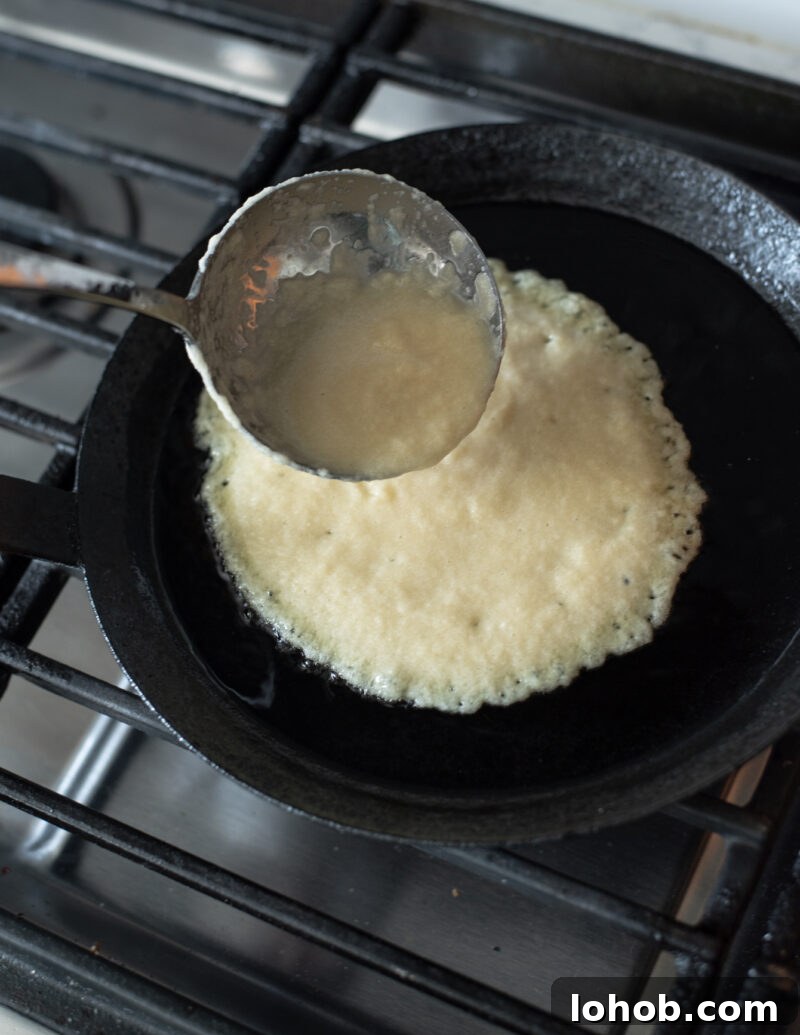 Potato pancake batter poured into a hot skillet to cook Korean gamja-jeon