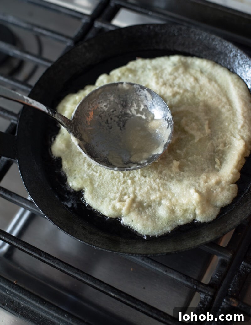 preading potato pancake batter in a skillet to form thin Korean gamja-jeon