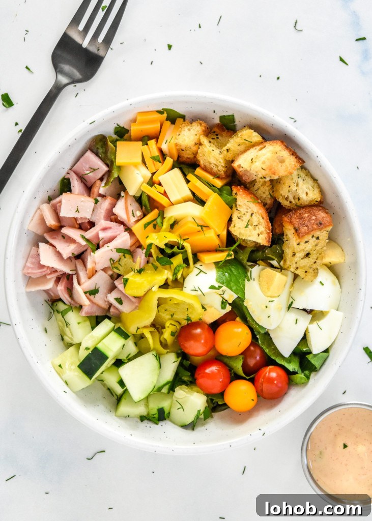 plated chef salad with fresh veggies, croutons, meat and cheese on a bed of romaine.