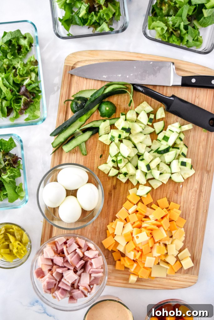 prepping and cutting all the ingredients for the chef salad on a cutting board.
