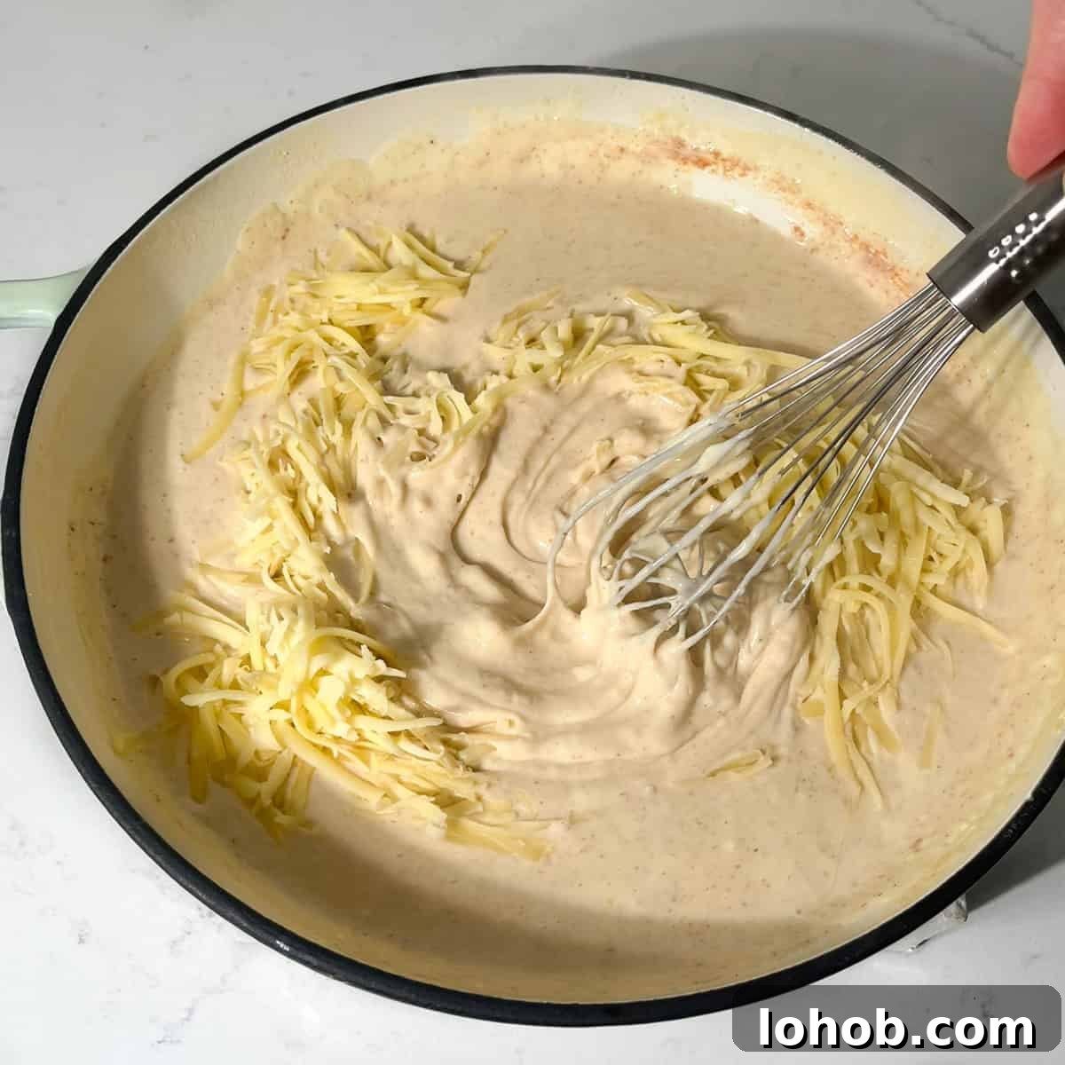 Creamy Baked Three-Cheese Macaroni with Garlic Parmesan Crumb Top 8 Mixing the cheese into the white sauce for the baked macaroni and cheese.