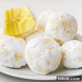 close up shot of white chocolate lemon truffles with a bite taken out of one on a plate