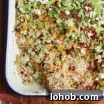 Spoon in baked rice topped with feta, pomegranate seeds and green tahini sauce.