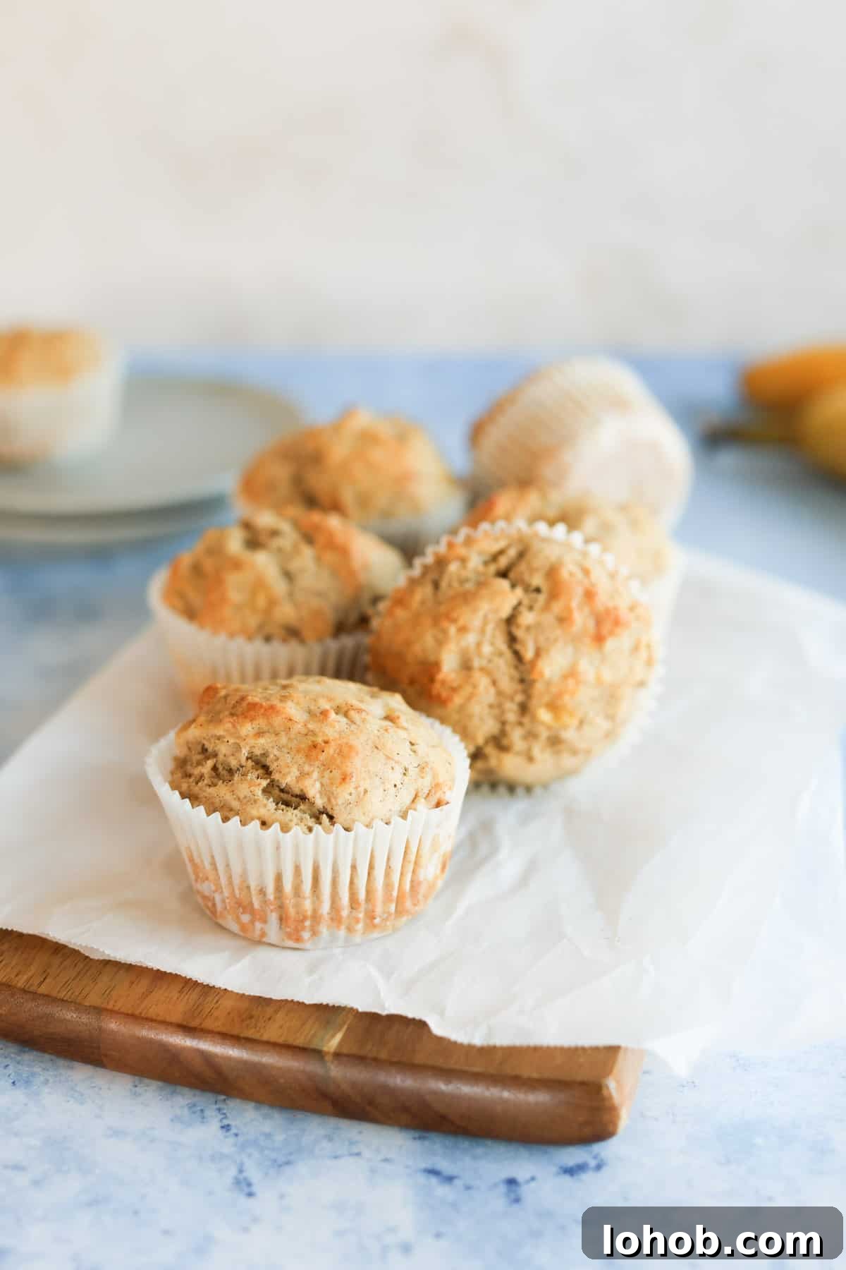 A group of banana bread muffins on a parchment paper-lined cutting board.