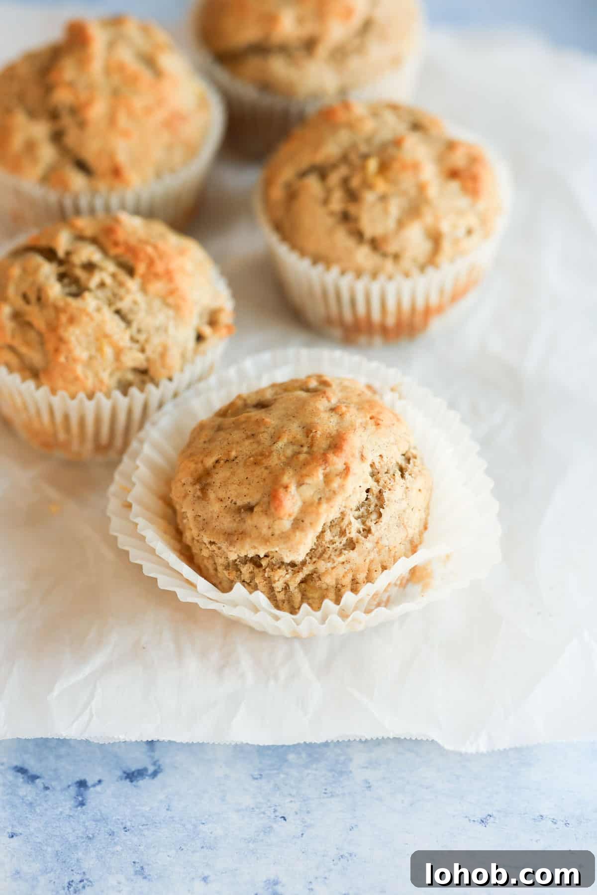 Four banana muffins on a white sheet of paper.