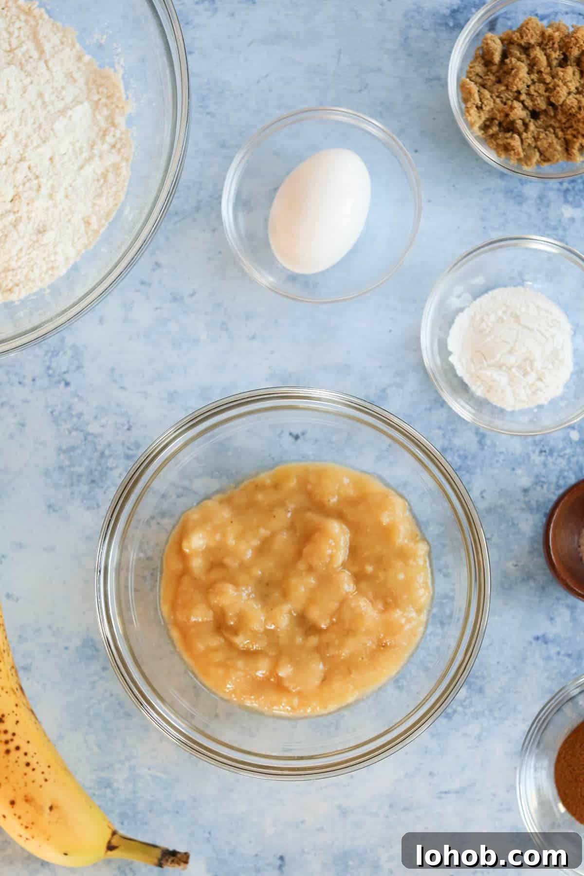 The ingredients for banana bread muffins are shown on a blue countertop.
