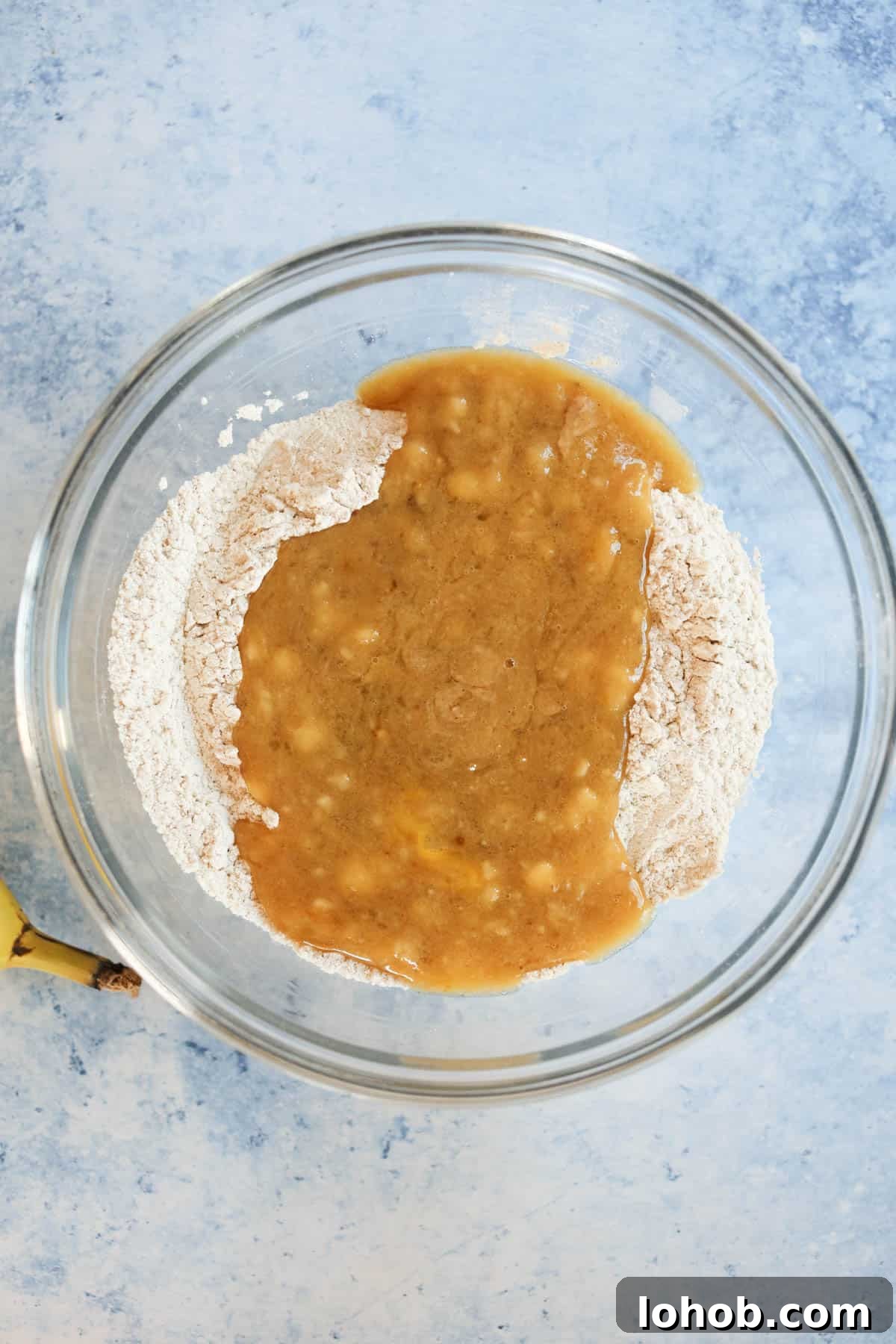 Mashed bananas and flour in a glass bowl.