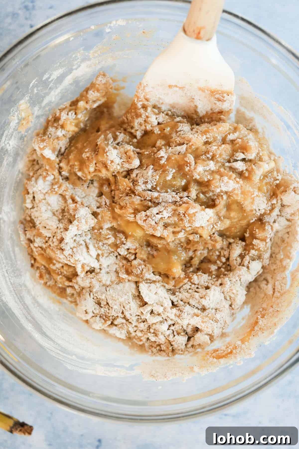 Banana bread muffin batter mixed together with a wooden spatula.