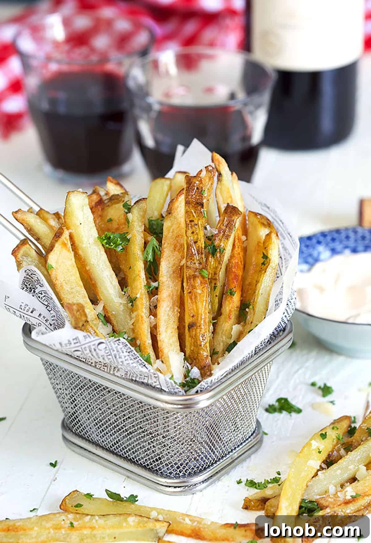 Crispy Parmesan Truffle Fries Recipe with Garlic and Herbs 2 Parmesan Truffle Fries in a wire fry basket with parsley and a glass of wine.