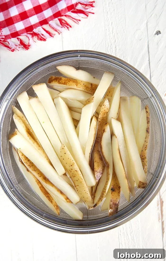 Crispy Parmesan Truffle Fries Recipe with Garlic and Herbs 4 potatoes cut into fries soaking in water