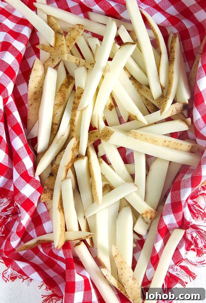 Crispy Parmesan Truffle Fries Recipe with Garlic and Herbs 5 Potatoes cut into fries in a kitchen towel.