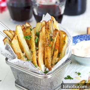 Crispy Parmesan Truffle Fries Recipe with Garlic and Herbs 8 Parmesan Truffle Fries in a wire fry basket with parsley and a glass of wine.