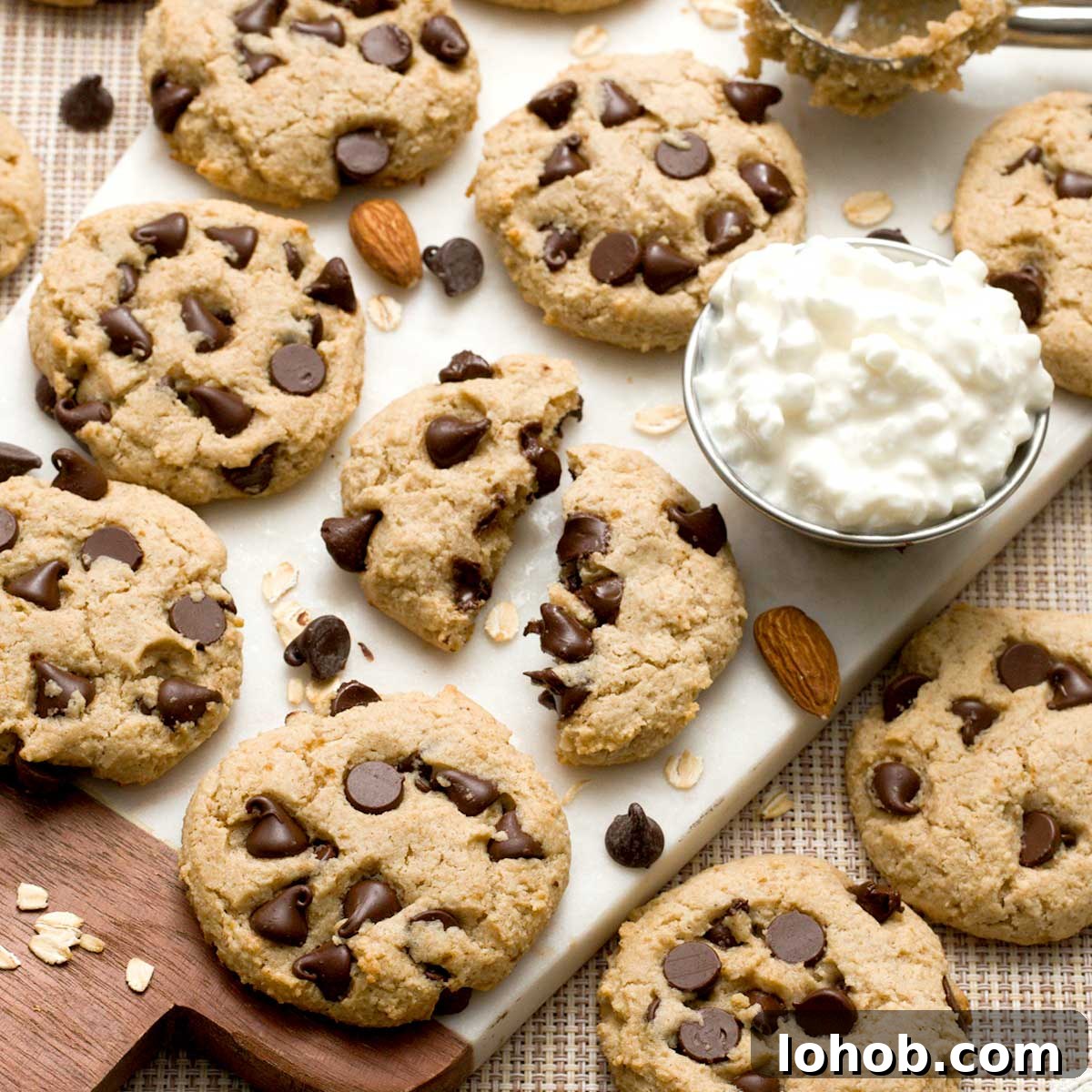Gluten-Free Peanut Butter and Jelly Thumbprint Cookies 13 Gluten-free cottage cheese chocolate chip cookies on a white cutting board with one cookie broken in half.