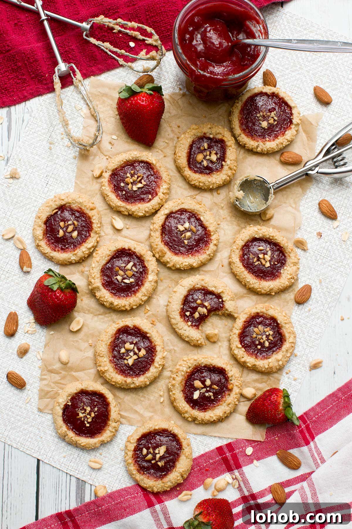 Gluten-Free Peanut Butter and Jelly Thumbprint Cookies 3 Top view of gluten-free peanut butter and jelly cookies on parchment paper.