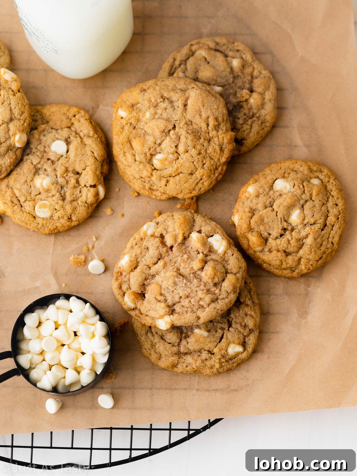 Chewy Apple Cinnamon Cookie Recipe for Soft, Spiced Treats 2 Apple cinnamon cookies with white chocolate chips on brown parchment paper.